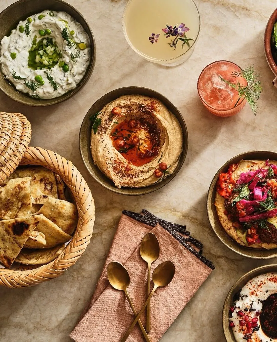 Tzatziki, hummus, and dips with pita and warm spices on a stone counter