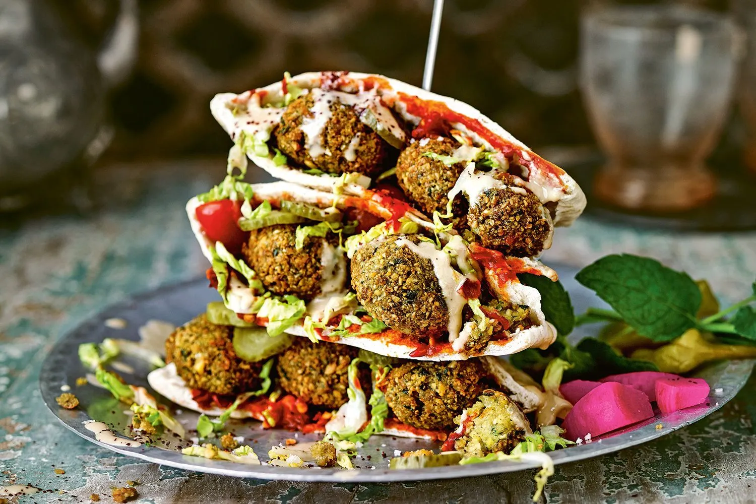 Falafel sandwiches stacked in pita with tahini, hot sauce, and pickles